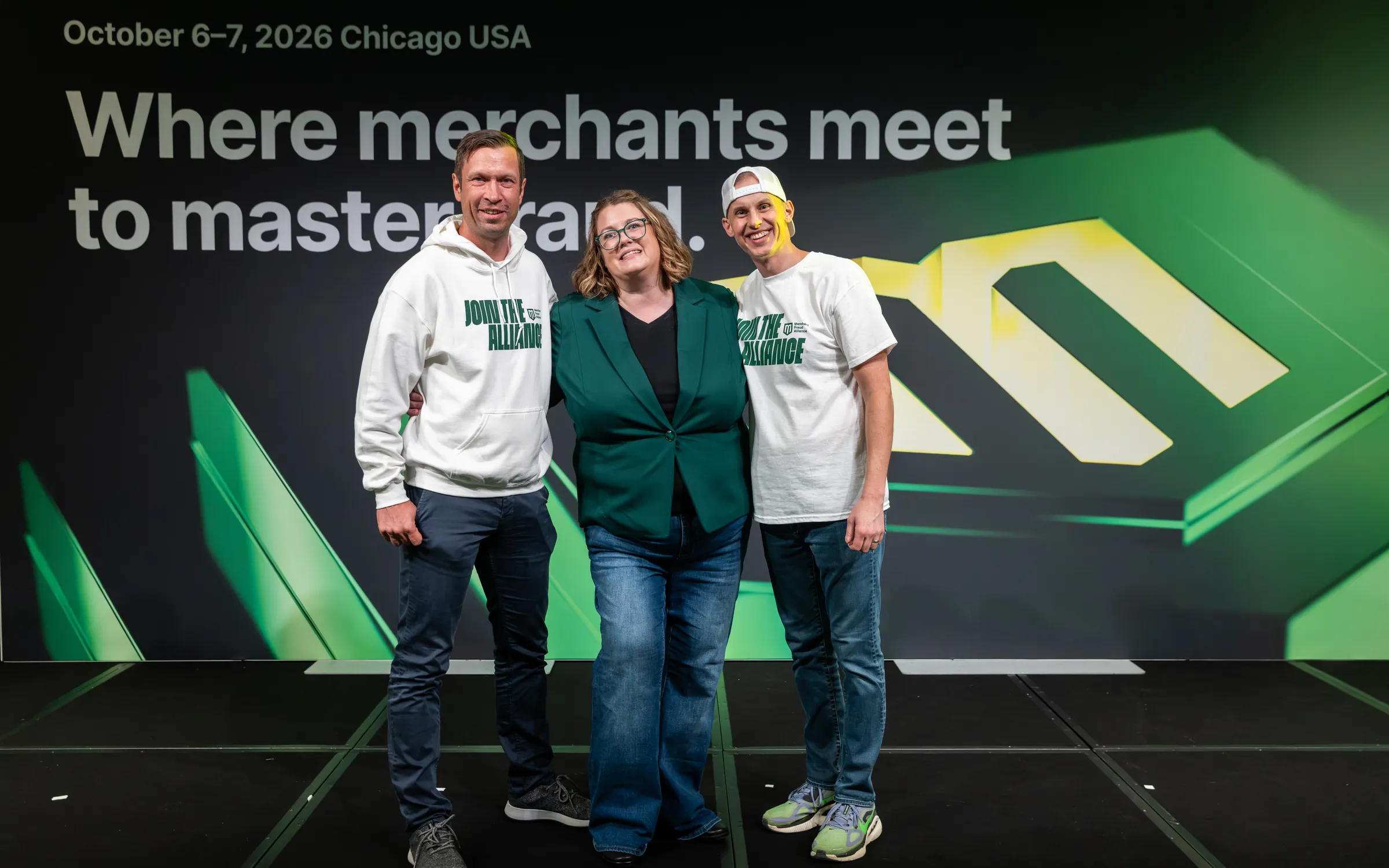 The three founders of the Merchant Fraud Alliance on the Main Stage, in Join the Alliance shirts, in front of “Where merchants meet to master fraud.”