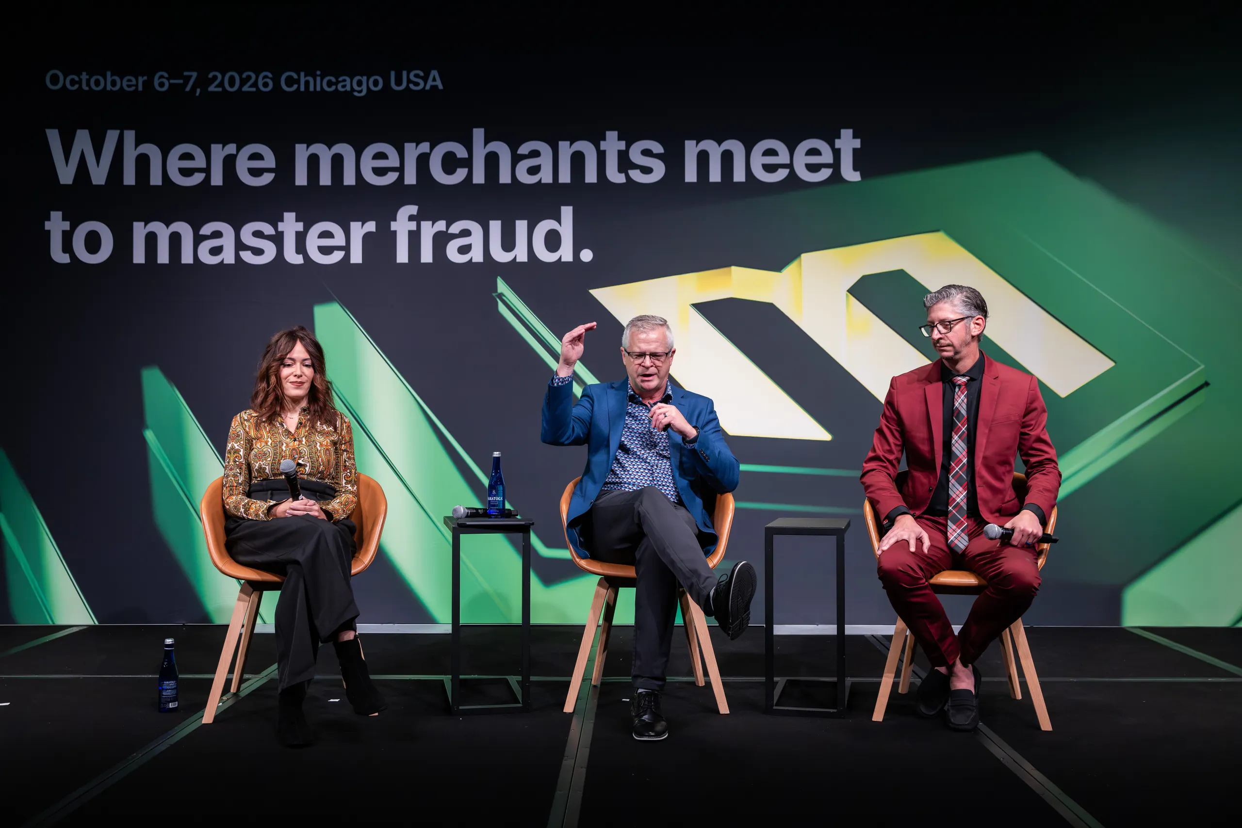 A panel of three speakers on the Main Stage in front of the green Merchant Fraud Alliance key visual and the line “Where merchants meet to master fraud.”