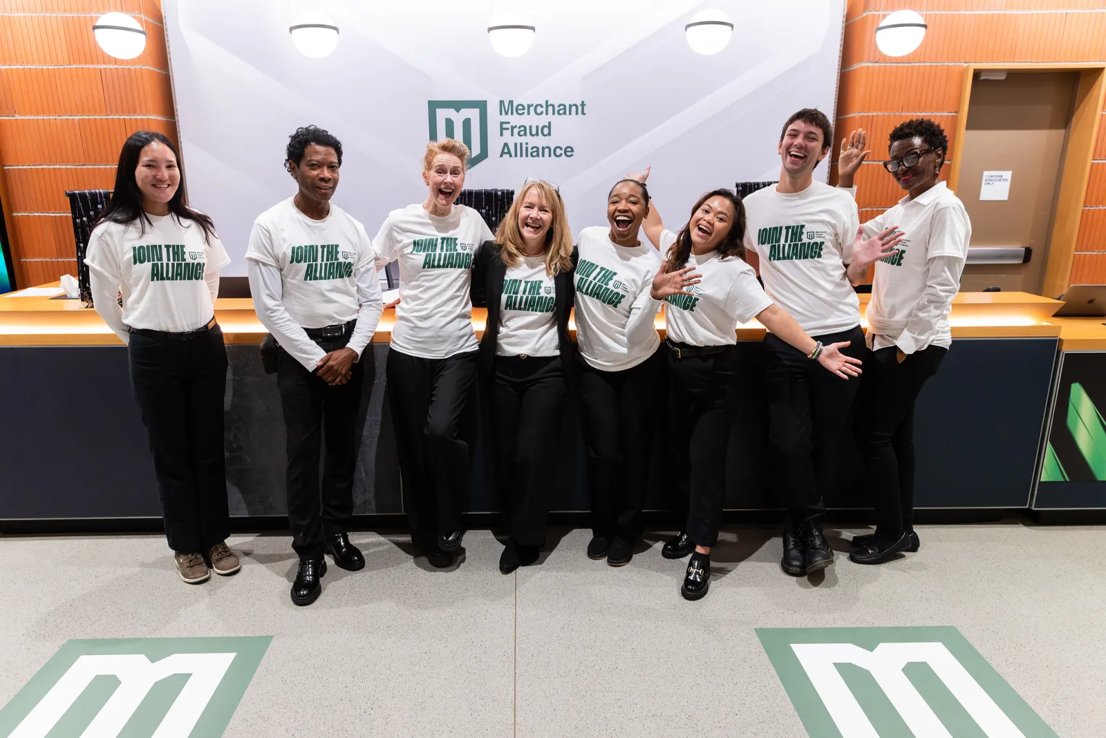 The event team in Join the Alliance shirts at the registration desk, with the M on the floor