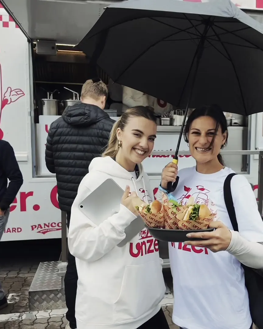 Two guests in Unzer hoodies with Berry Red fries in front of the truck