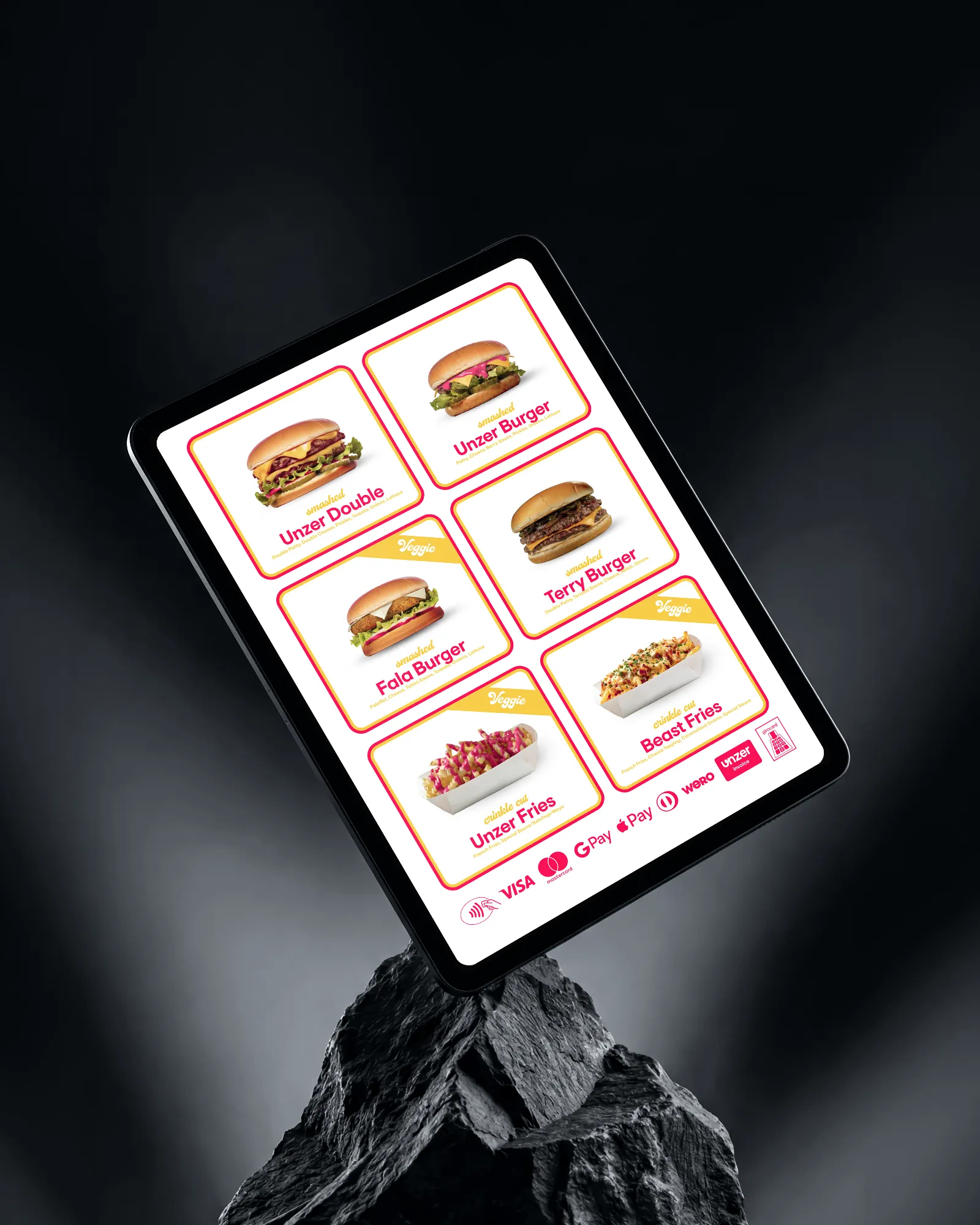 Tablet on a rock showing the menu board with six burgers and fries and every way to pay