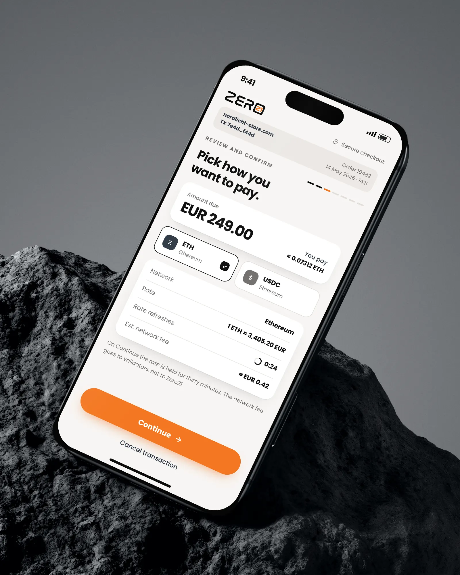 Phone on a rock showing the review screen with network and amount